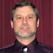 Man with short dark hair and salt and pepper beard and mustache